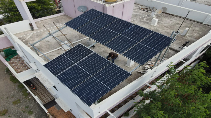 Rooftop view in Jaipur, Rajasthan, featuring a man standing beside solar panels for renewable energy.