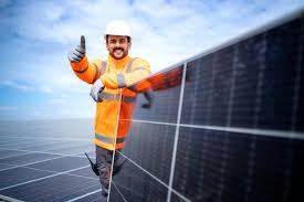  A man wearing an orange and black uniform presents a solar panel and blueprint, highlighting solar energy in Jaipur, Rajasthan.