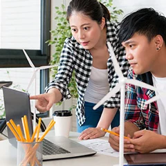 Two team member focus on a laptop, with planing solar energy in view, representing the integration of technology and renewable energy